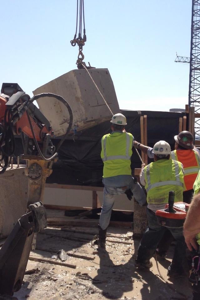Select Concrete Services workers moving a block of concrete held up by a crane